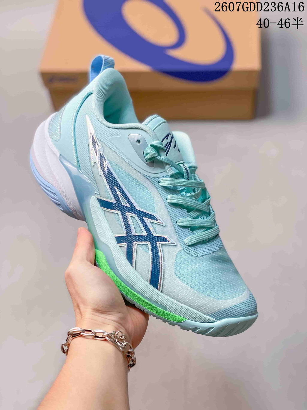 Side view of an aqua ASICS basketball shoe showing the blue side branding, lace-up closure and green outsole accent.