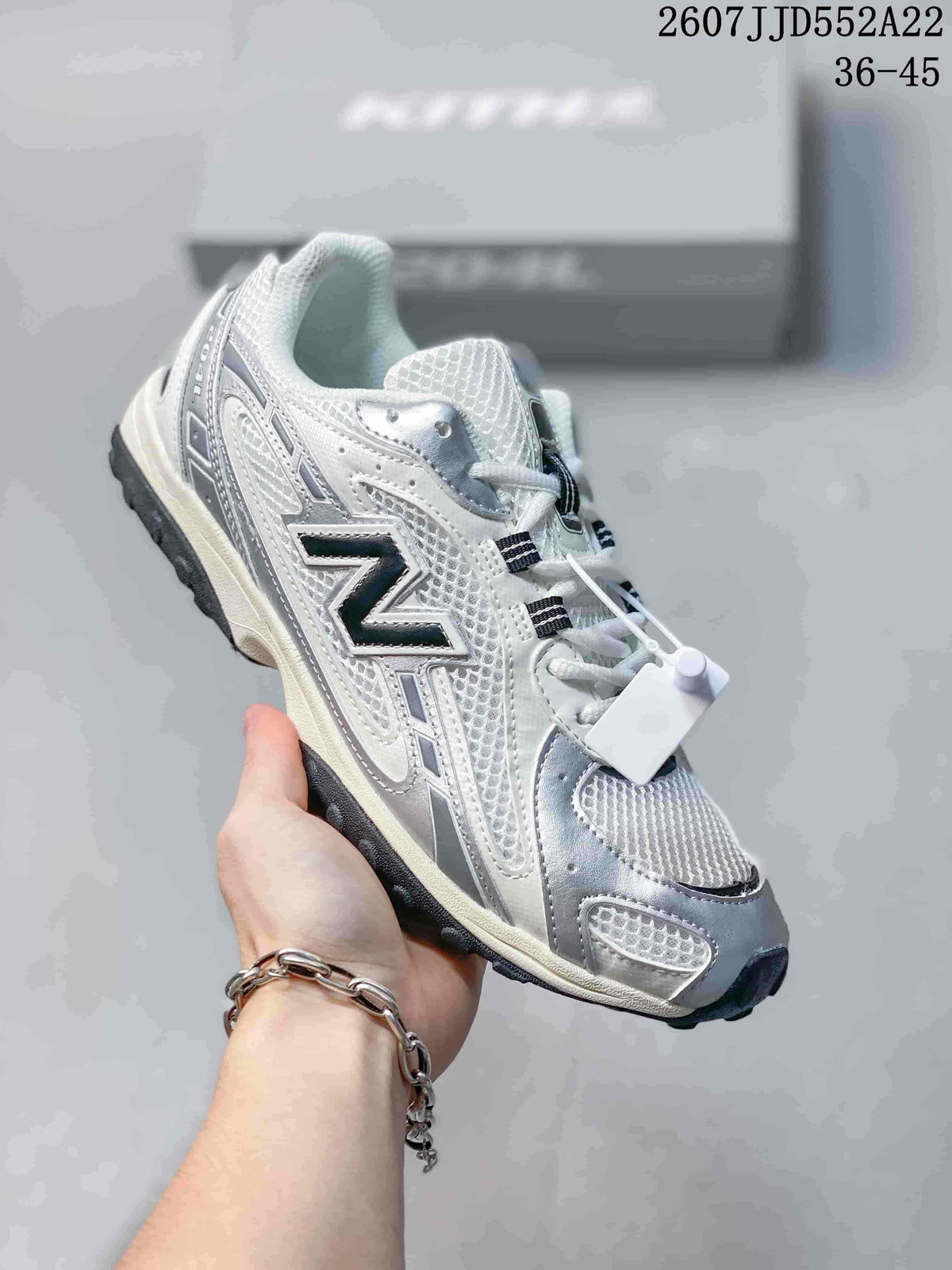 Three-quarter side view of the white and silver sneaker showing the layered upper, dark side logo, lace-up design, and black outsole.
