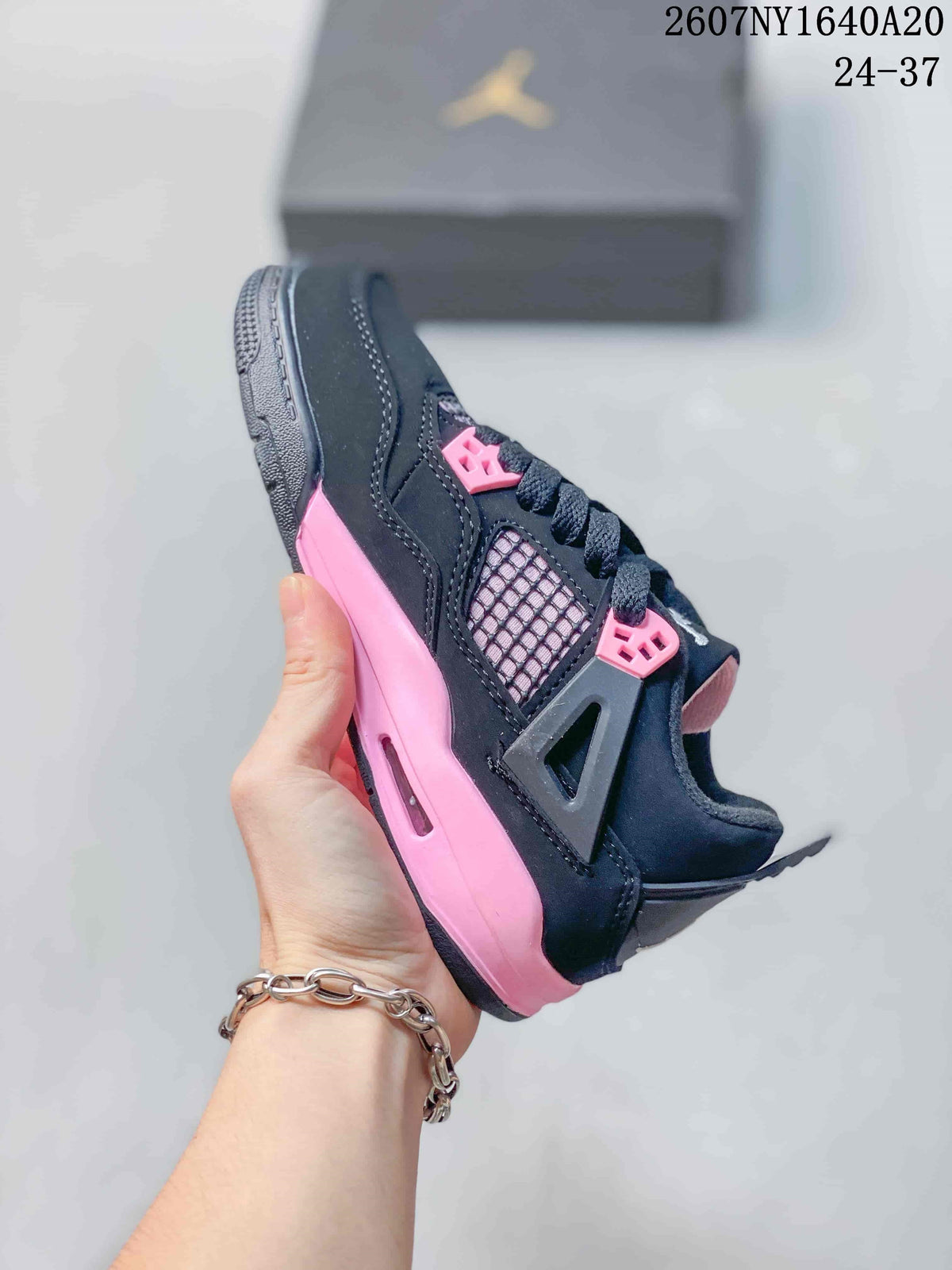 Side view highlighting the black upper, mesh panel, pink midsole accent, and lace system.