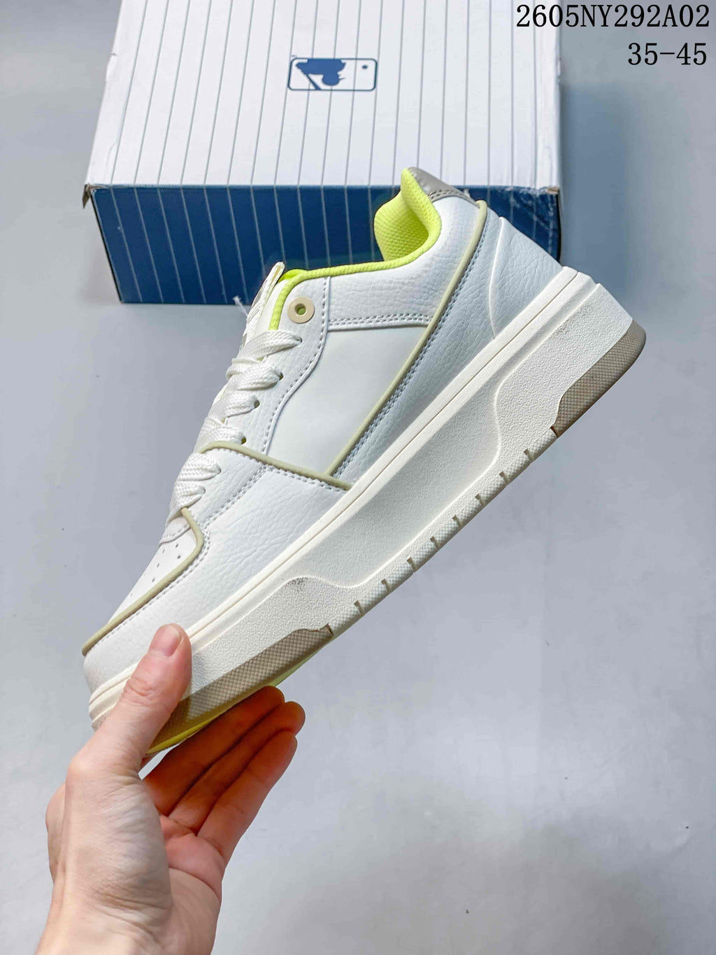 Side view of the white low-top sneaker showing its layered sole, stitched panels, and green accents.