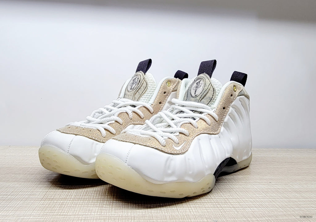 Front three-quarter view of white Air Foamposite One sneakers with marbled beige overlays and white laces.