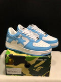 Blue and white BAPE STA low-top sneakers displayed on a camouflage shoebox; the box label shows US 7, EUR 40, and CM 25.