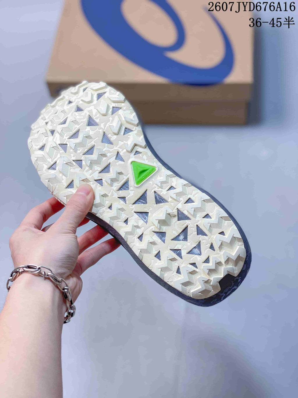 Close view of the patterned outsole with multi-directional tread blocks and a green accent section.