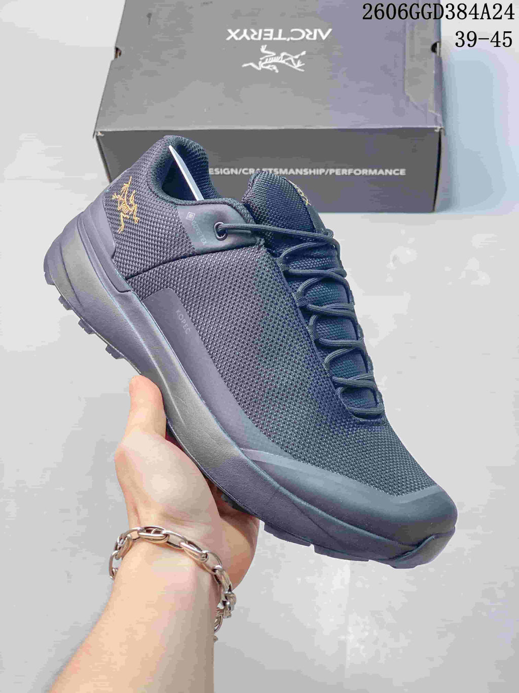 Angled side view showing the shoe's dark gray upper, gold-tone logo, and lugged sole