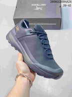 Angled side view showing the shoe's dark gray upper, gold-tone logo, and lugged sole