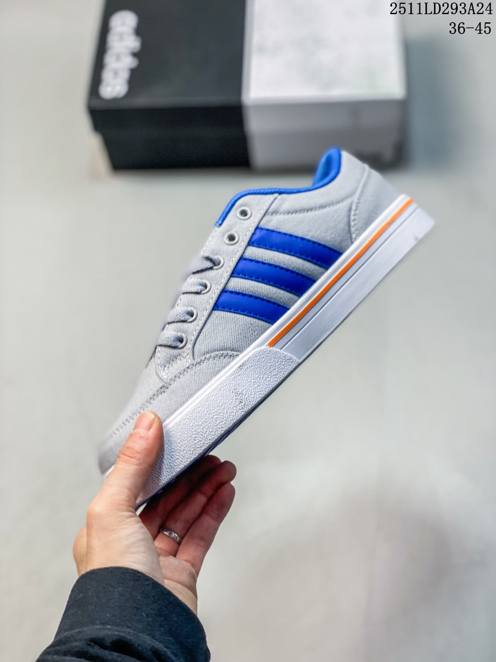 Side profile of the grey sneaker with blue stripes, white outsole and orange accent stripe.