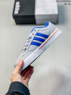 Side profile of the grey sneaker with blue stripes, white outsole and orange accent stripe.