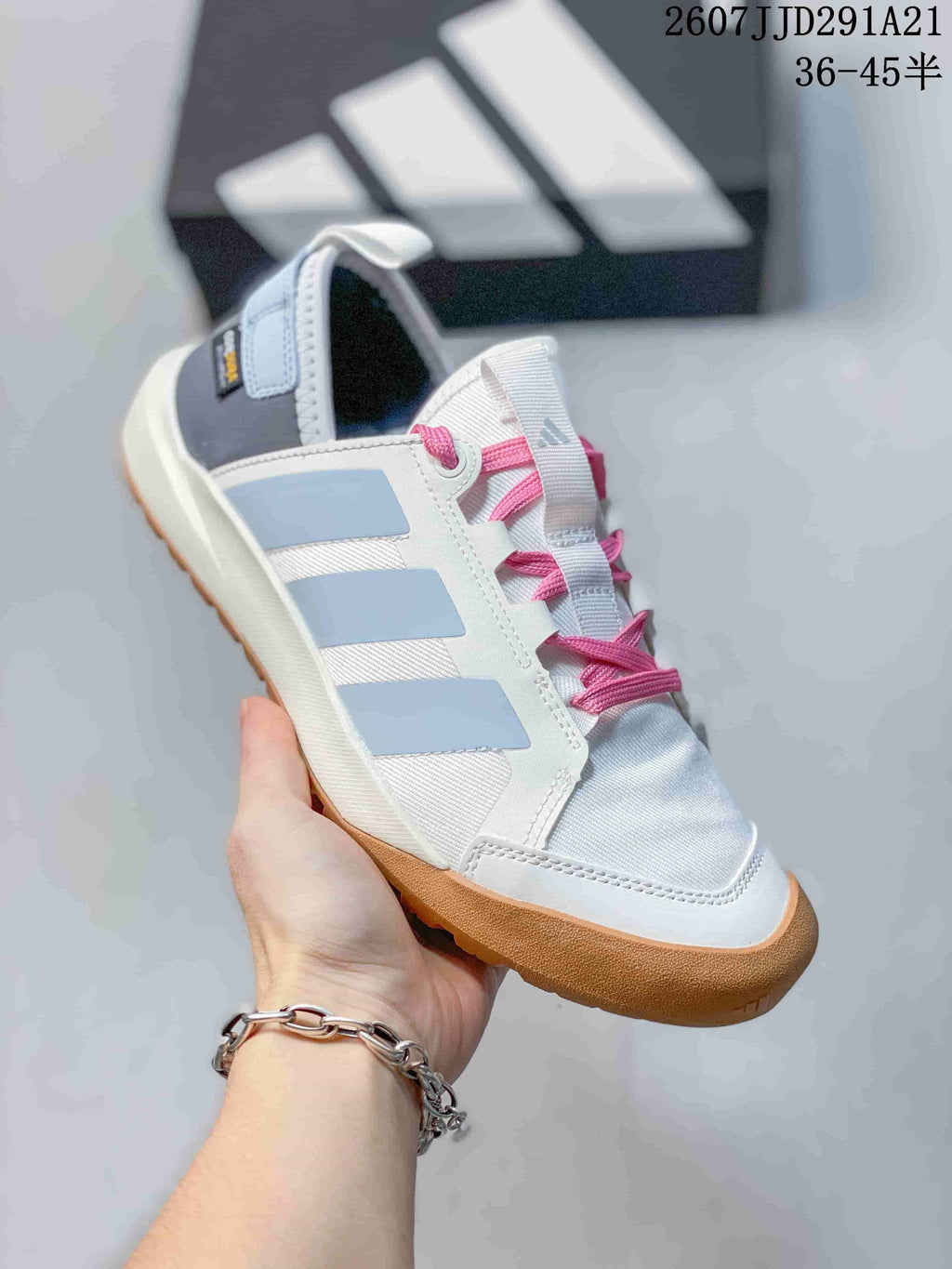 Angled side view of the white and pale blue outdoor shoe with pink laces and a gum-colored treaded sole.