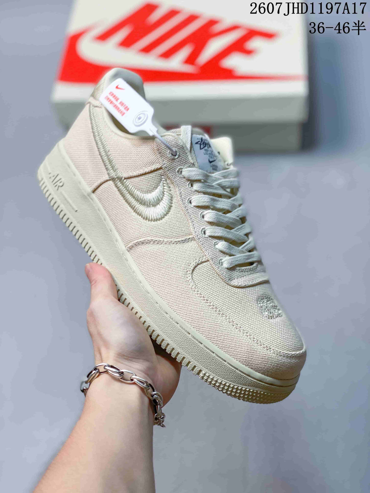 Angled side view of the cream sneaker showing the embroidered Swoosh, woven upper, tonal midsole, and outsole.