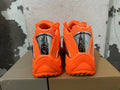 Rear view of bright orange low-top sneakers with silver-tone heel accents.
