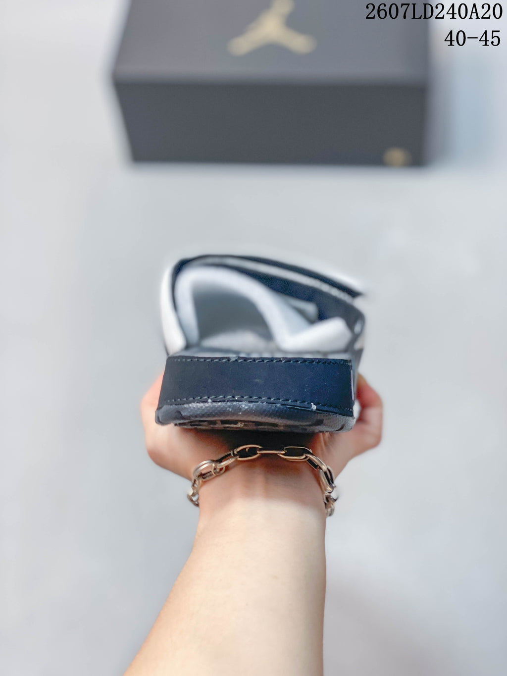 Rear view of a white and navy slide showing the padded heel area, layered sole, and stitching.