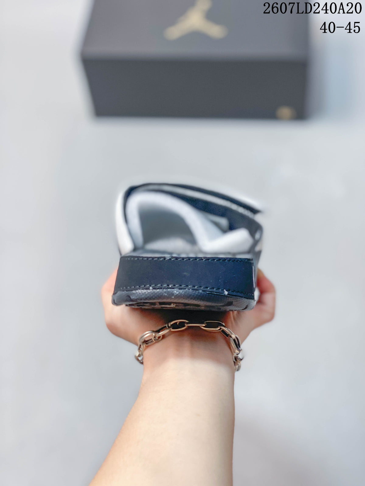 Rear view of a white and navy slide showing the padded heel area, layered sole, and stitching.