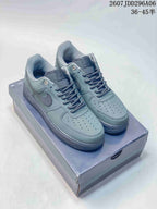 Pair of gray-green Nike low-top sneakers displayed on a shoebox, with a tonal Swoosh and dark outsole.