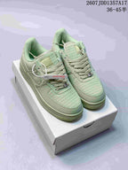 Pair of pale green Nike Air Force 1 ’07 low-top sneakers displayed on a white shoe box.