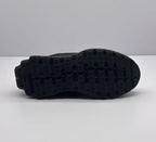 Underside view of the sneaker showing the black outsole with a segmented patterned tread.