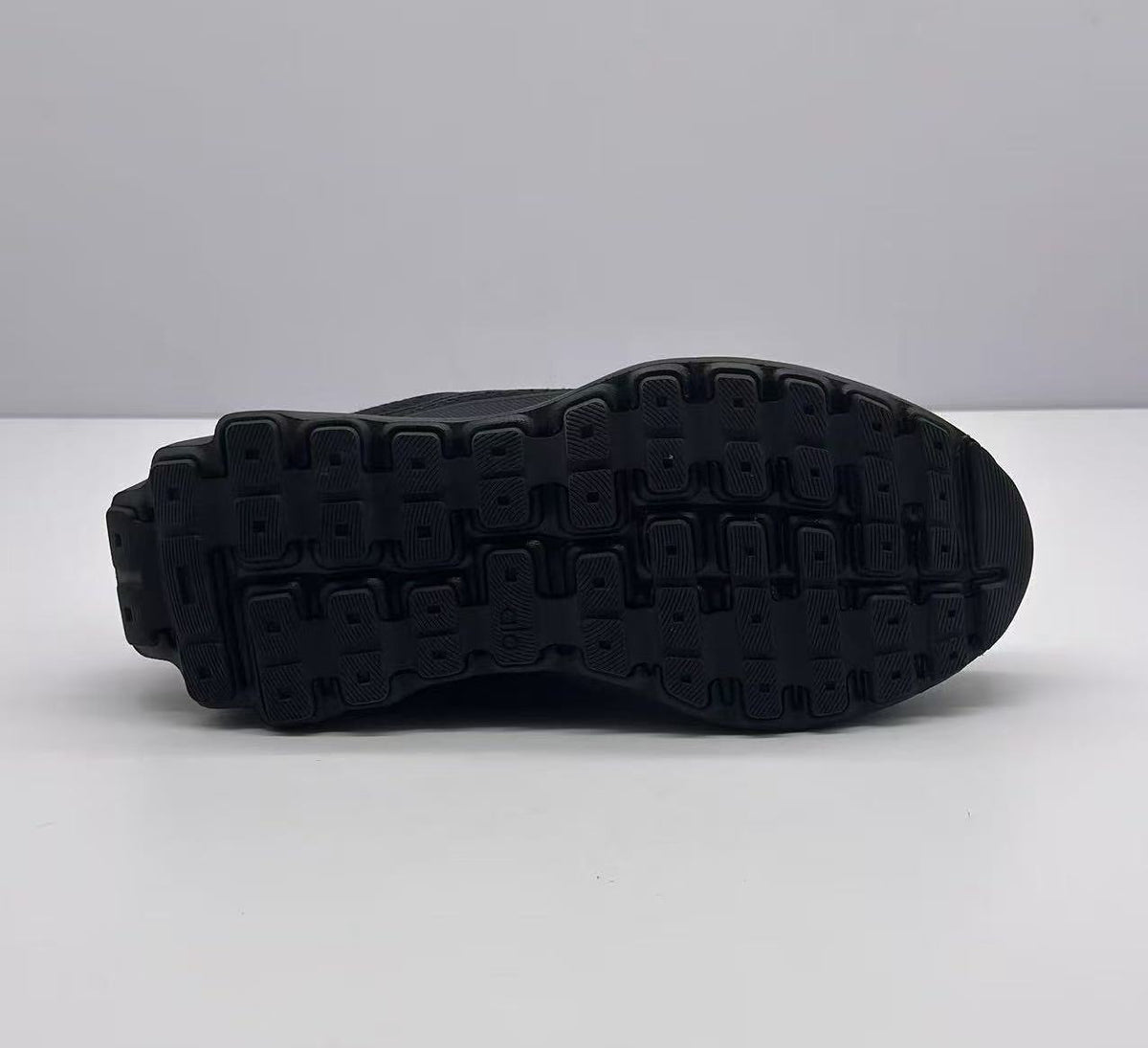 Underside view of the sneaker showing the black outsole with a segmented patterned tread.