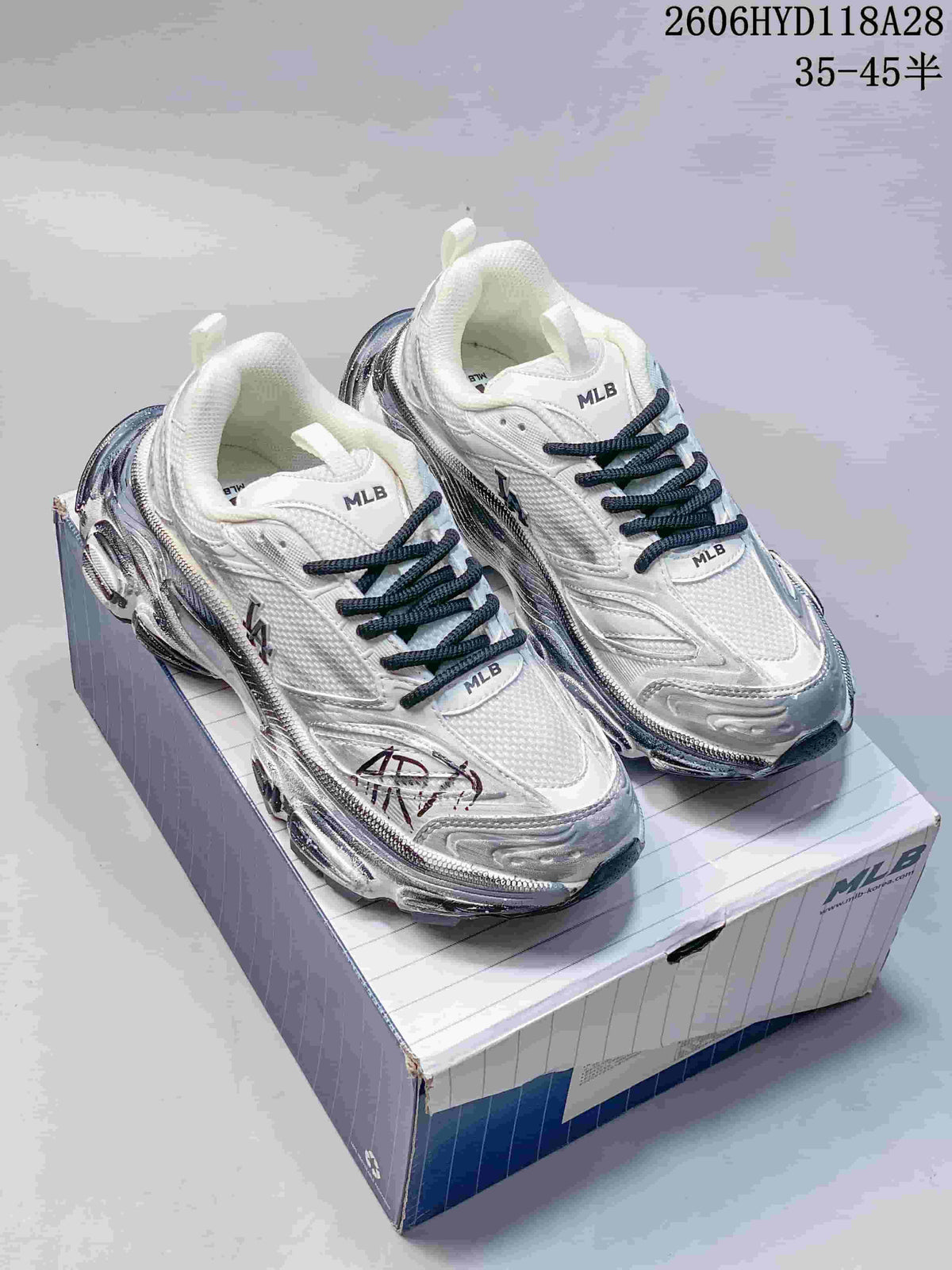 Pair of white and silver-toned MLB sneakers with dark laces and chunky soles