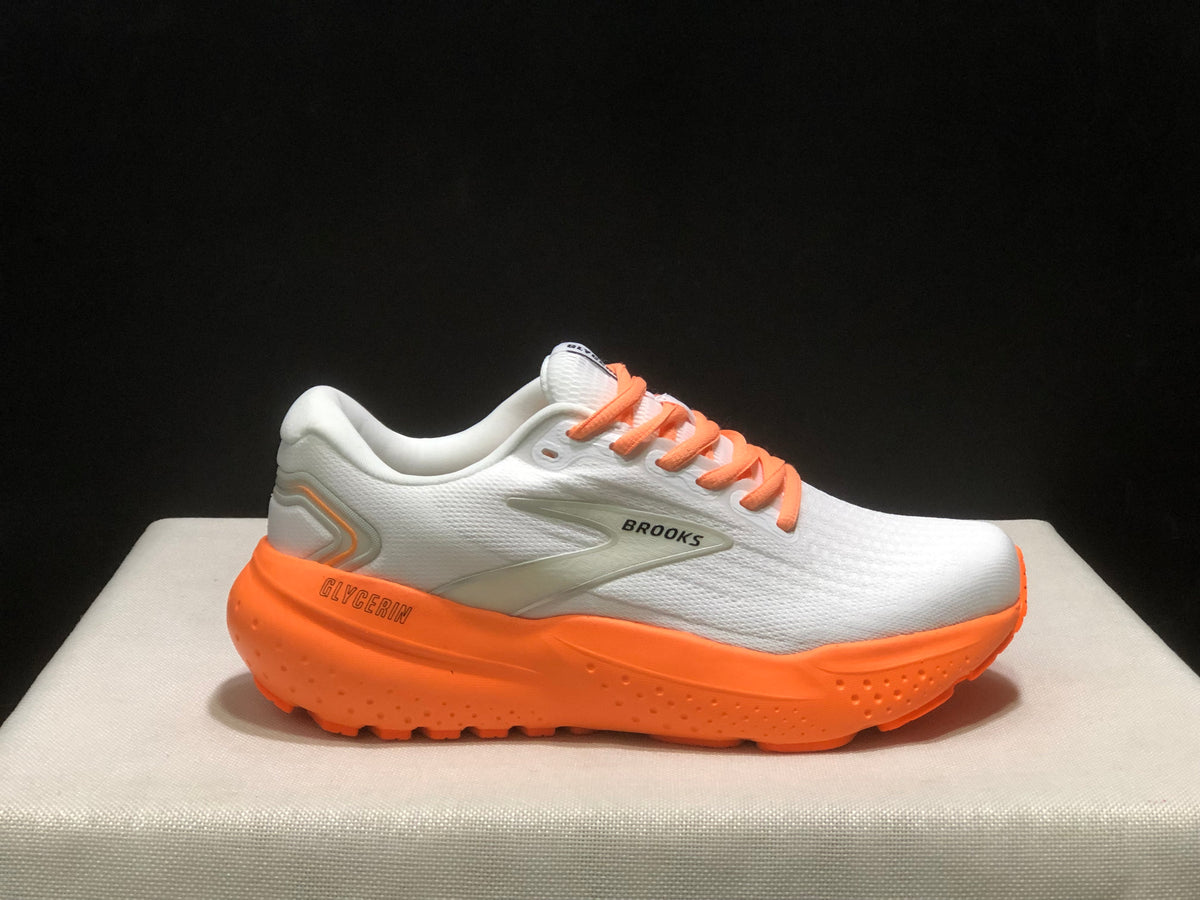 Single side profile of a white Brooks Glycerin 21 sneaker with orange laces and an orange outsole.