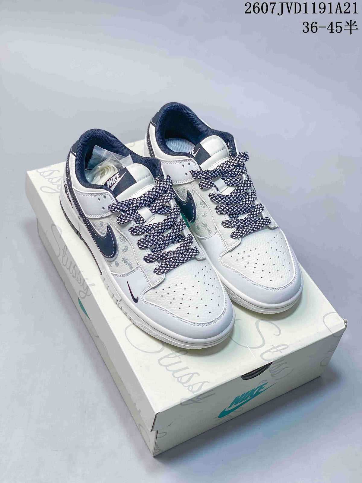 Pair of white and dark-accent Nike SB Dunk Low sneakers displayed on a branded shoebox; image text shows style code 2607JVD1191A21 and size range 36–45.