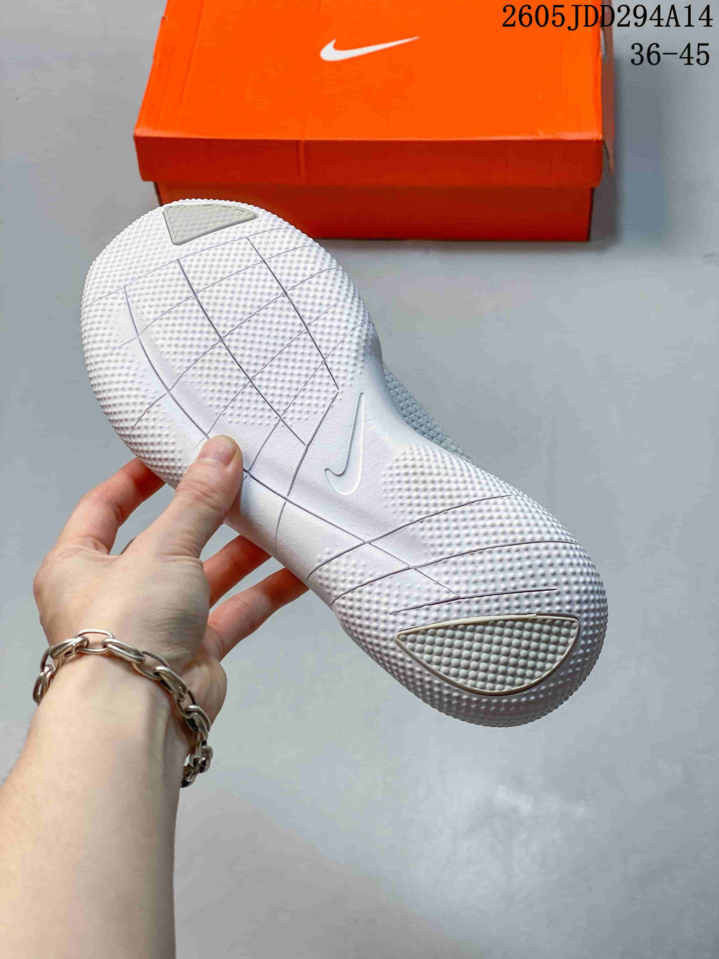 Underside view of the white Nike sneaker outsole showing segmented flex grooves and textured traction areas.
