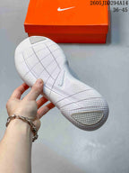 Underside view of the white Nike sneaker outsole showing segmented flex grooves and textured traction areas.