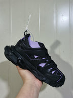 Close angled view of the black and lilac sneaker showing the sock collar, lace area, and structured side panels.