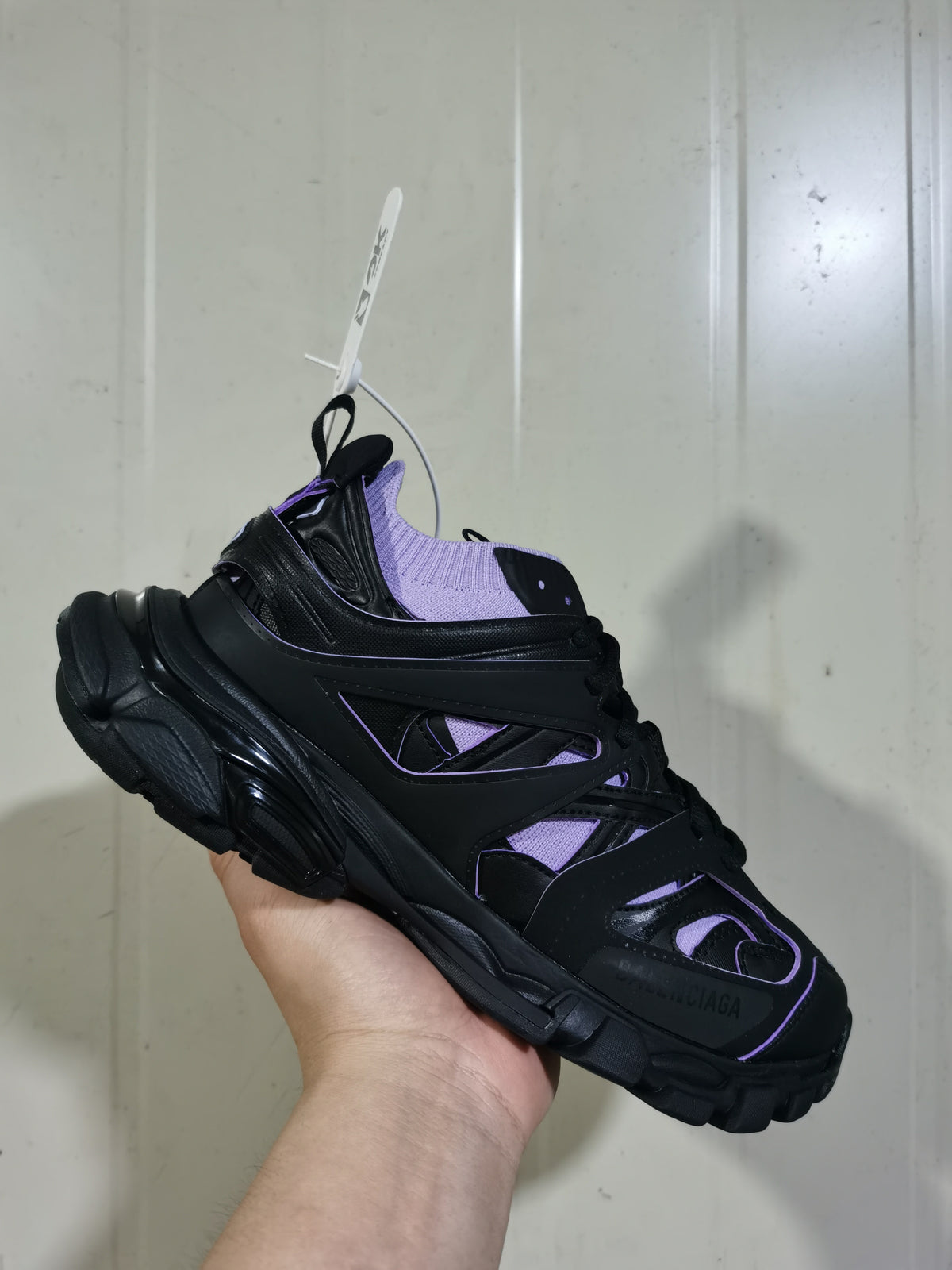 Close angled view of the black and lilac sneaker showing the sock collar, lace area, and structured side panels.