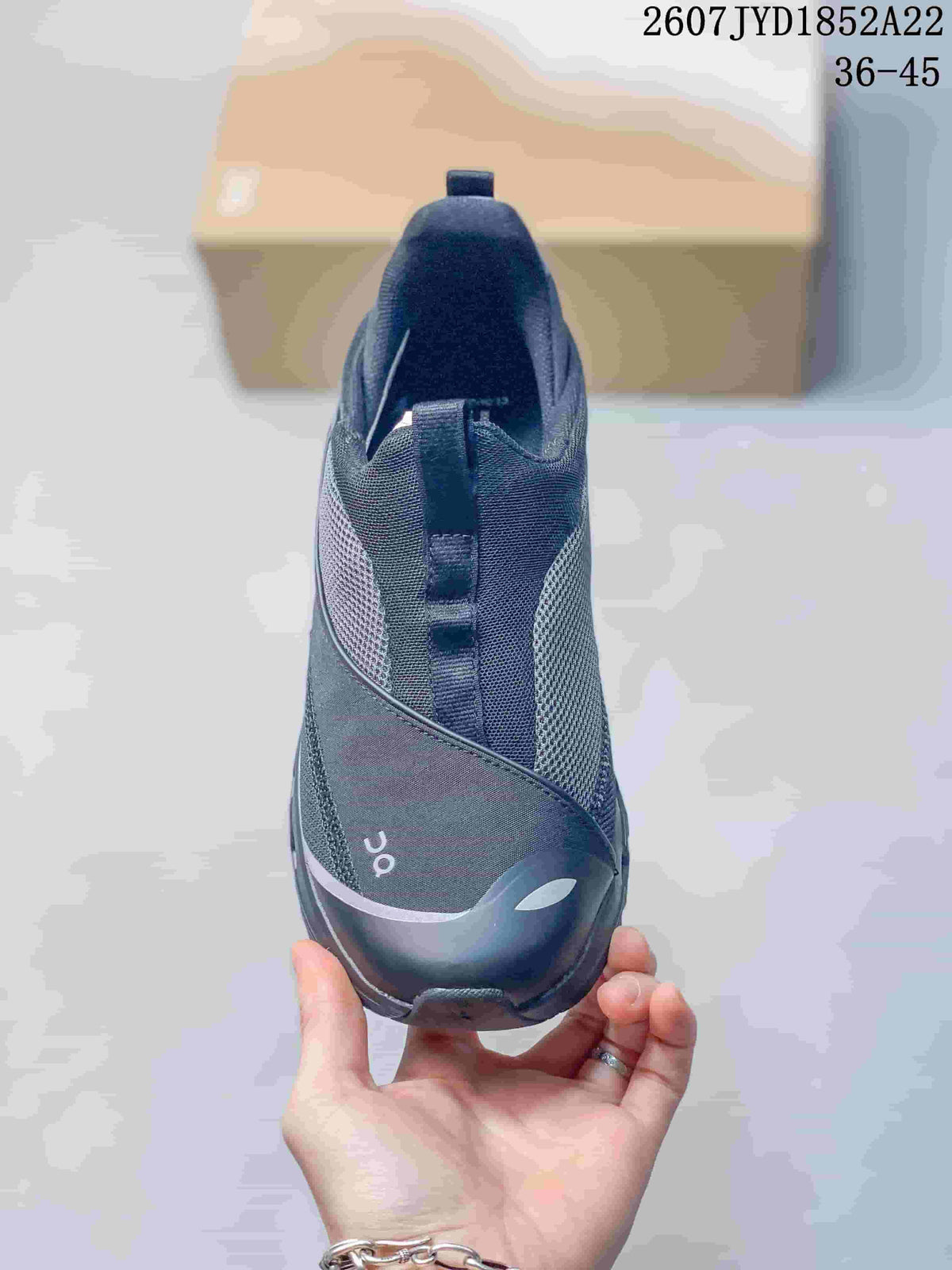 Front view of a black On sneaker showing the rounded toe, reflective-looking trim and tongue pull tab.