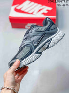 Side view of a gray Nike V5 RNR sneaker showing layered overlays, mesh-style panels, and the sculpted midsole.