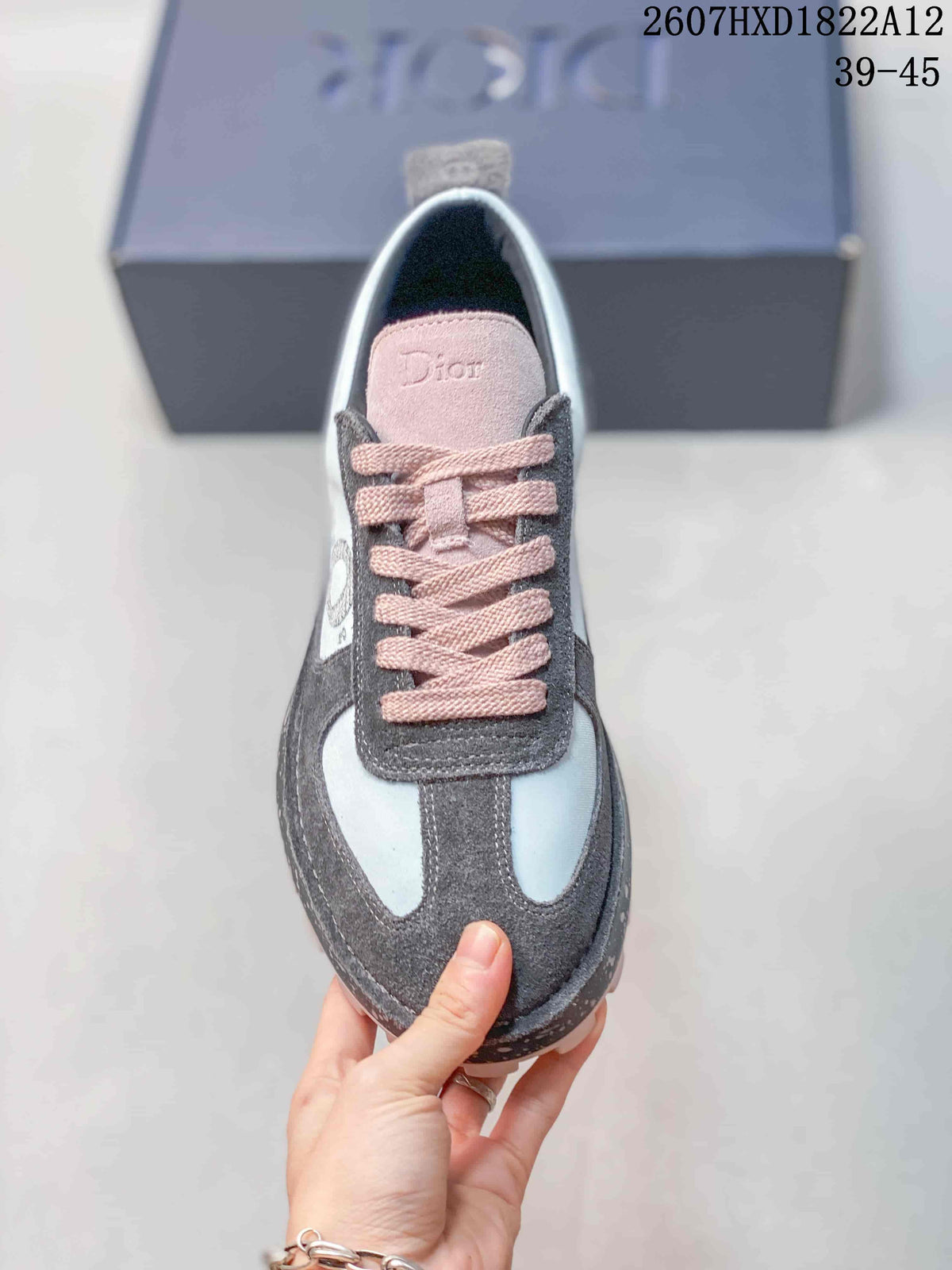 Top view of one sneaker showing the gray and white upper, pink laces, and pink Dior-branded tongue.