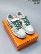 Pair of white and green low-top Nike sneakers displayed on an orange shoebox, with green laces and contrasting side Swooshes.
