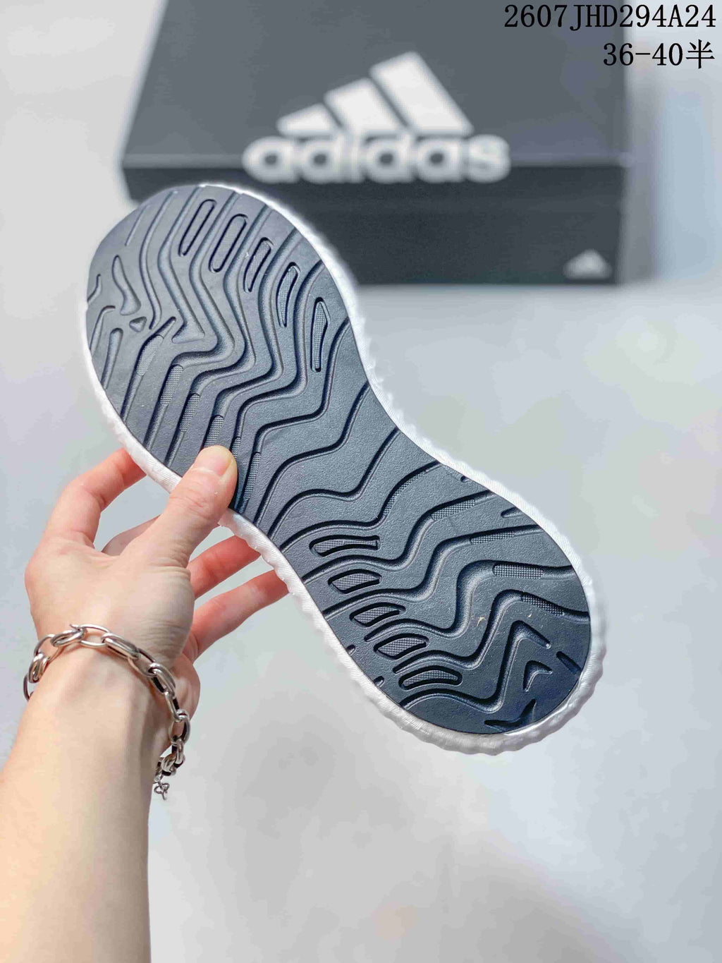 Underside view of the sneaker showing the dark patterned outsole with wavy traction grooves.