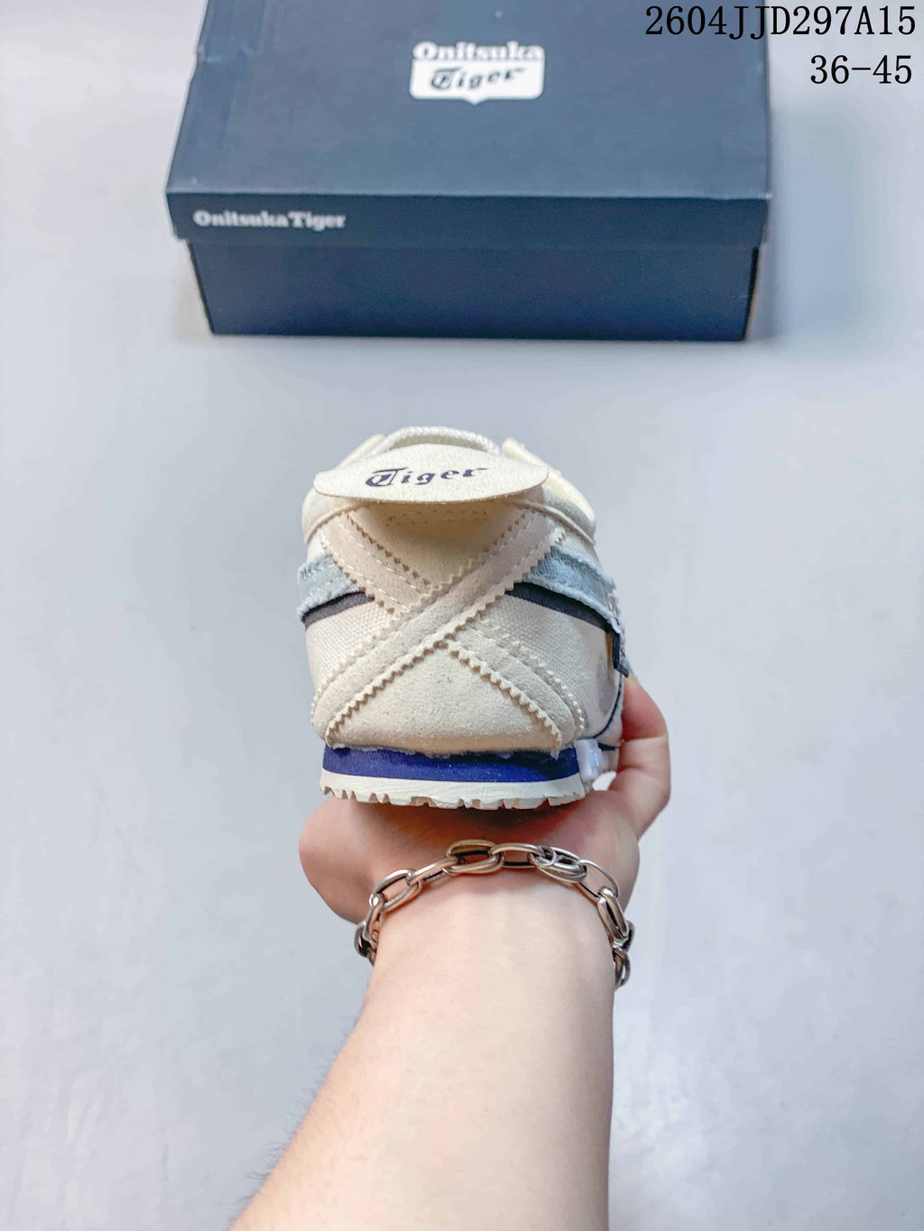 Rear view of the sneaker showing the layered heel construction, cream upper, blue accent, and branded heel tab.