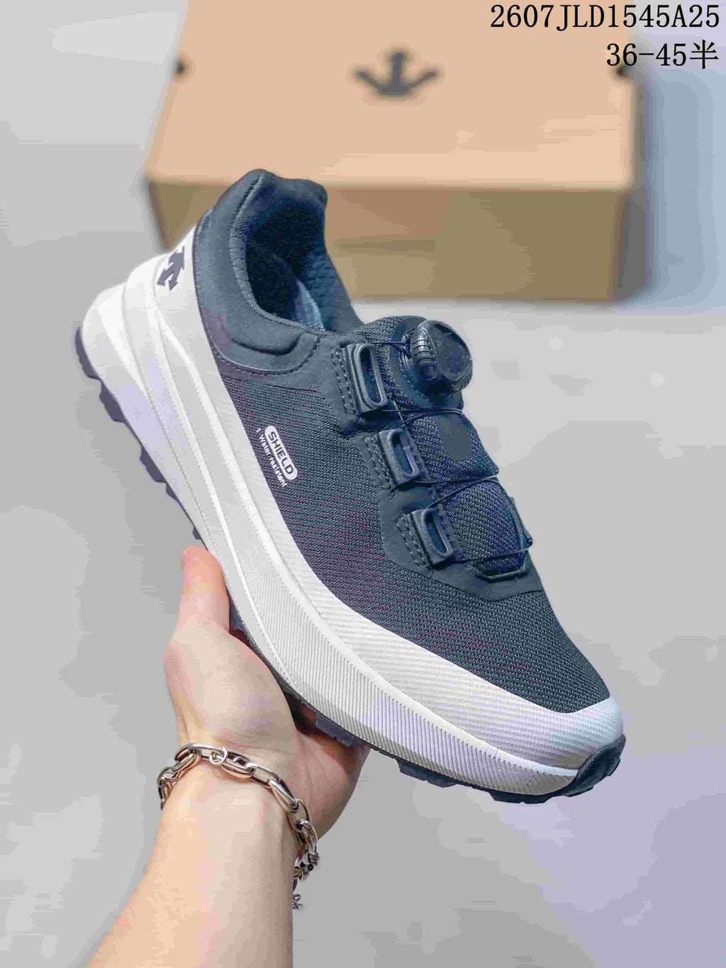 Three-quarter view of the dark low-top sneaker with SHIELD side branding and white midsole.