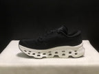 Side profile of one black sneaker showing the On logo and white segmented midsole.