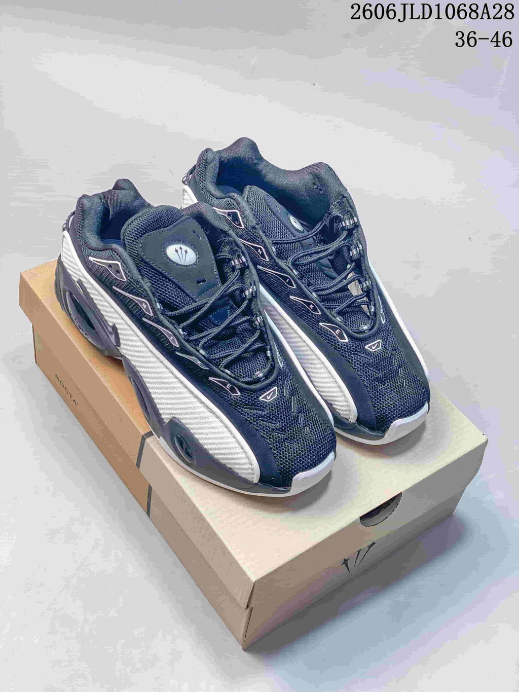 Pair of black and white Nike NOCTA Glide sneakers shown from above on a box.