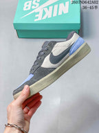 Side profile showing gray overlays, pale neutral panels, a blue heel accent, and a speckled sole