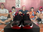 Front view of black and red Air Jordan 11 sneakers with glossy toe overlays.
