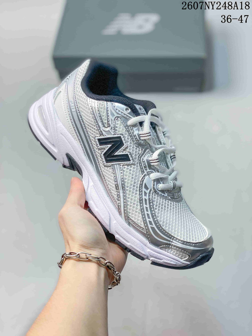 White and silver New Balance 740 sneaker with black detailing and a dark logo.