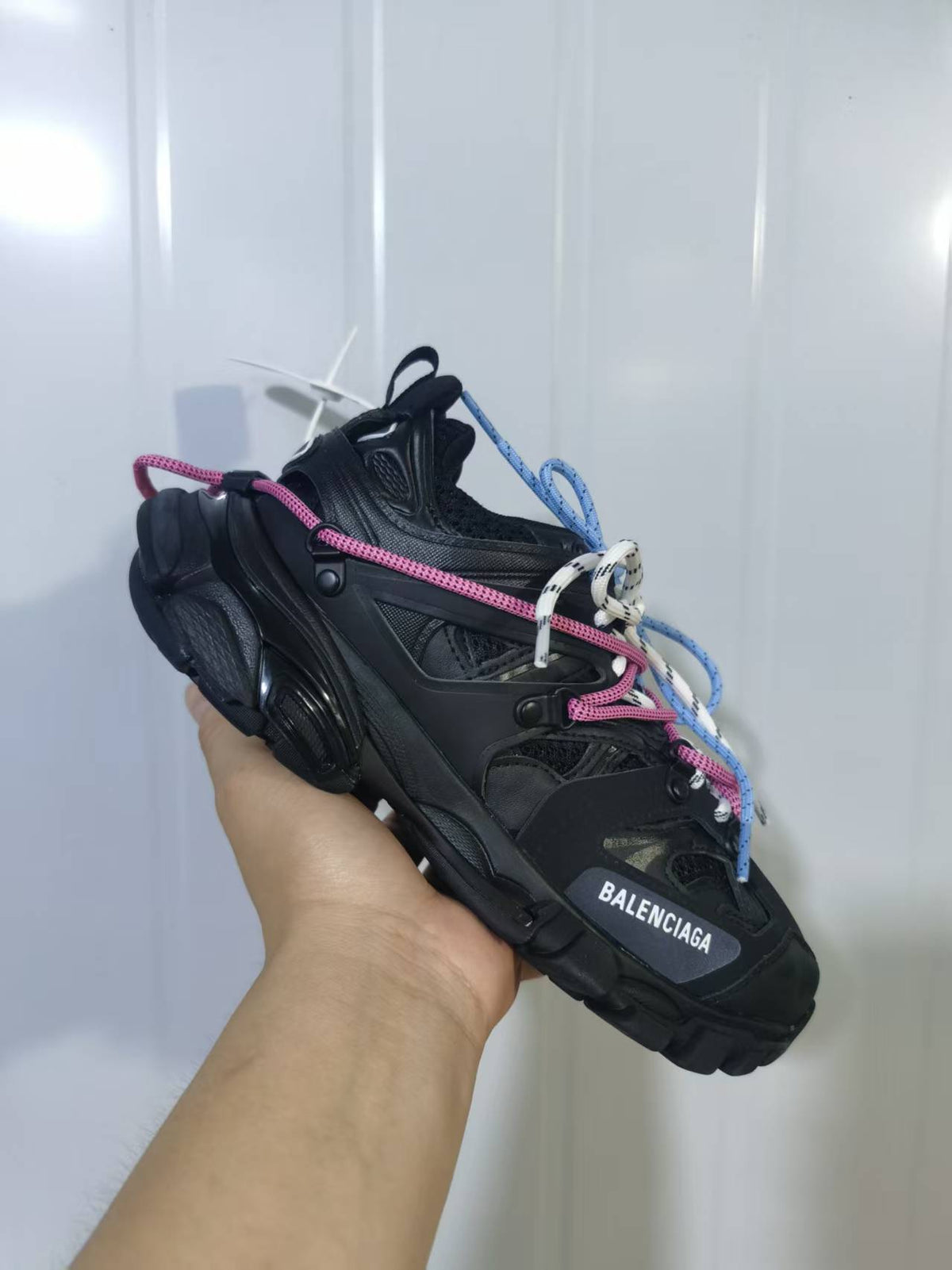 Close angled view of a black Balenciaga Track Trail sneaker showing the textured upper, layered construction, multicolored laces, and visible toe branding.