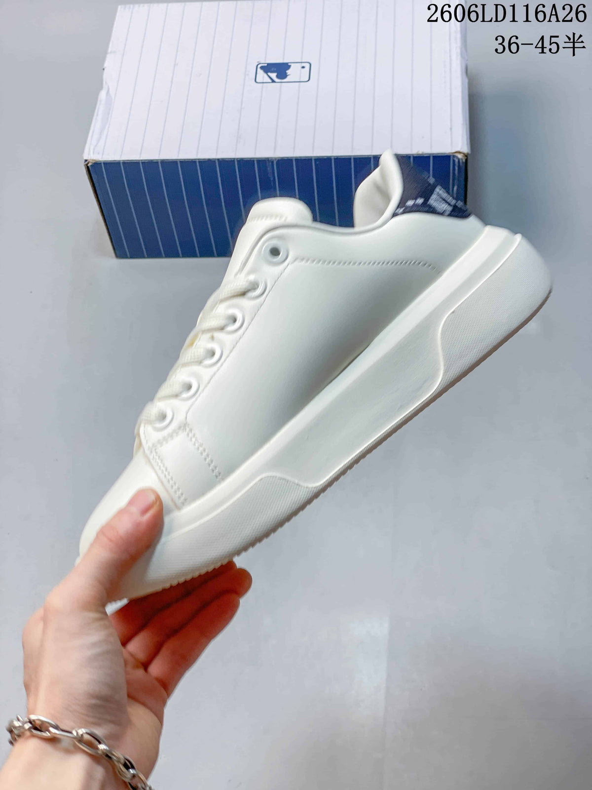 Side view of the white low-top sneaker showing its smooth upper, lace eyelets, padded collar, and raised sole.