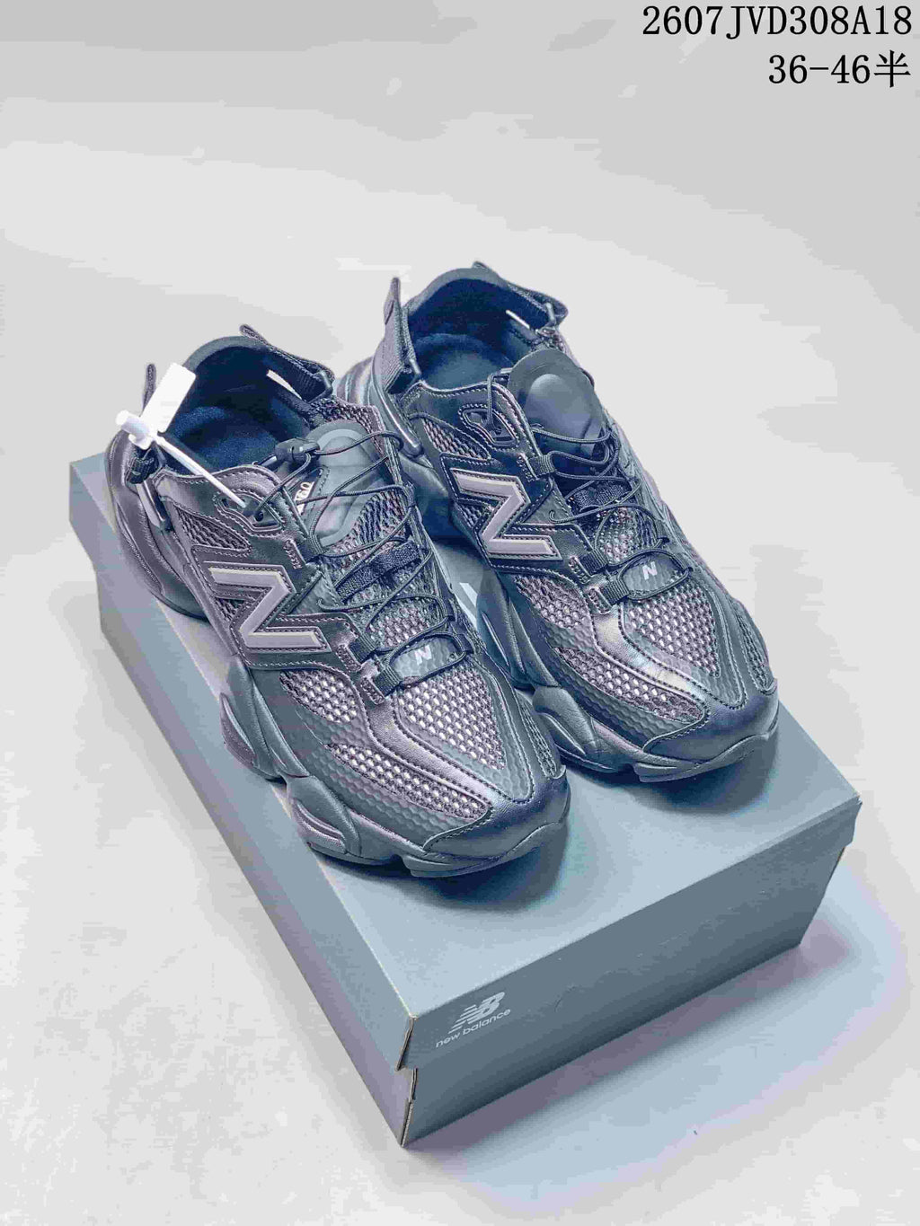 Pair of dark New Balance 9060 sneakers displayed on a branded shoebox; style code 2607JVD308A18 and size range 36–46 are visible at the top.
