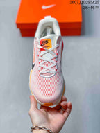 Top view of a Nike Vomero 18 sneaker showing the mesh-look pink and white upper, laces, and orange tongue label.