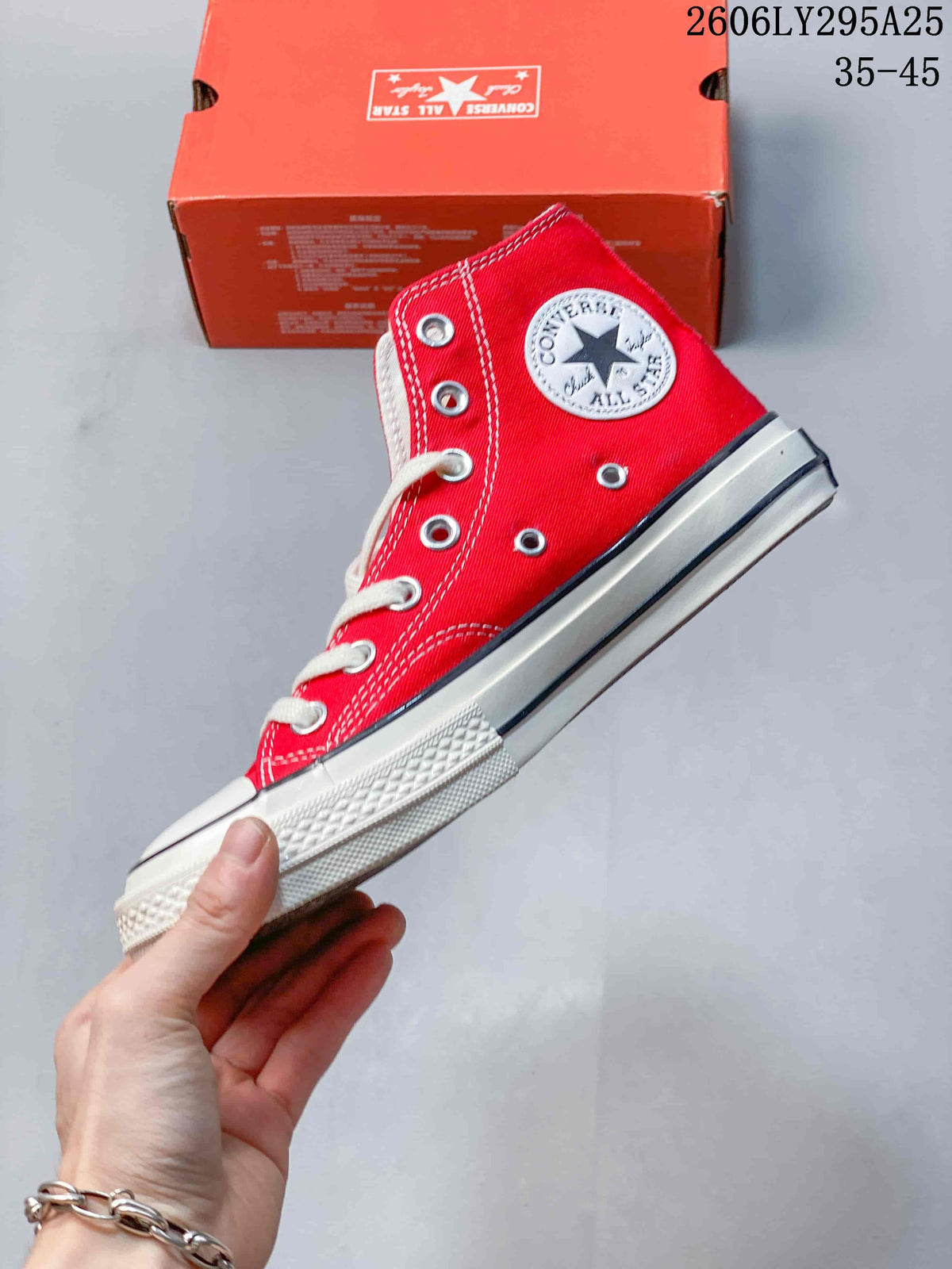 Side view of the red high-top sneaker showing the ankle patch, metal eyelets, contrast stitching, and rubber sole.