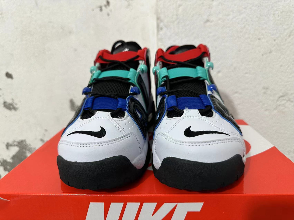 Front view of white sneakers with black detailing and red, teal, and blue accents.