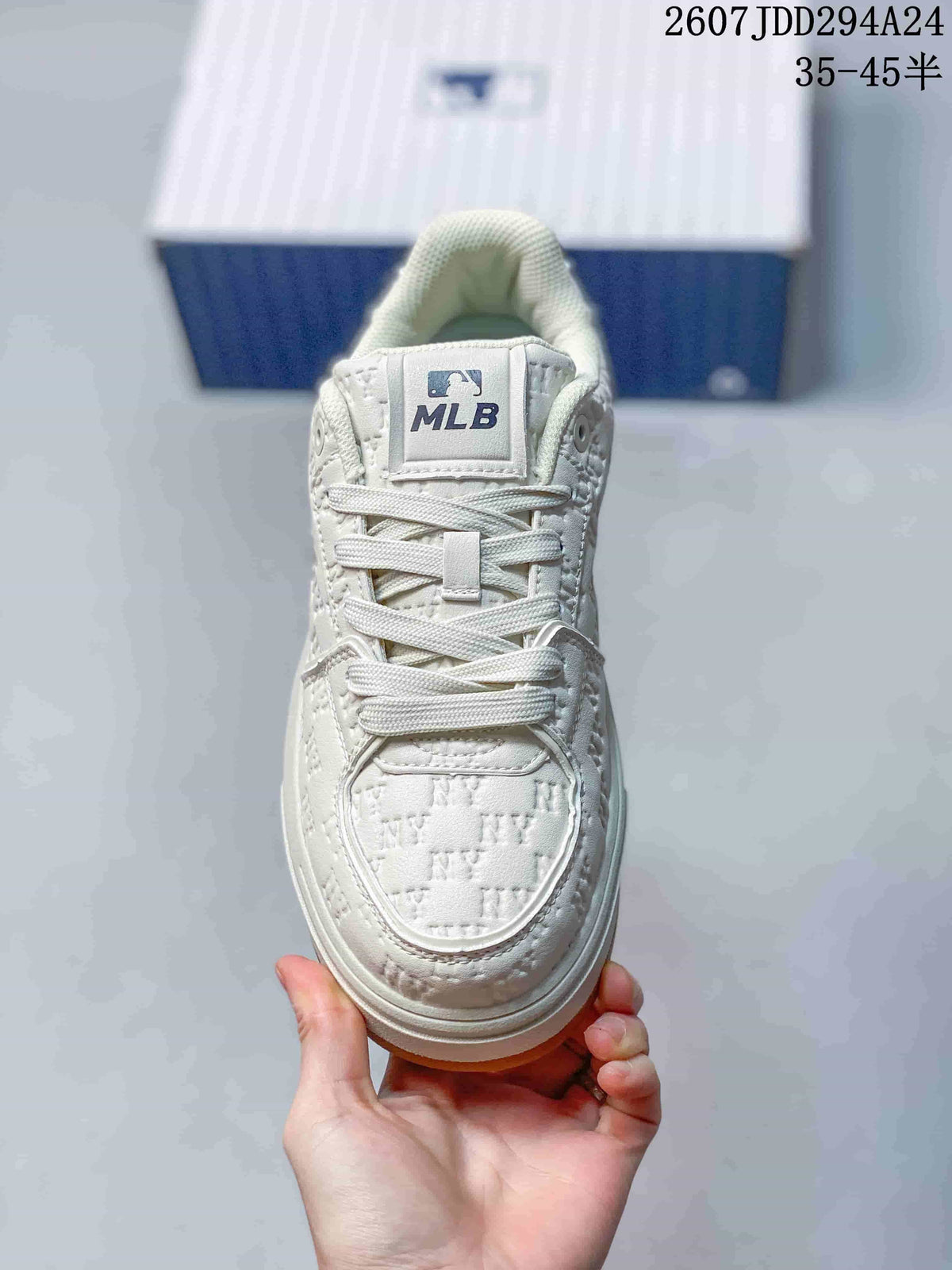 Front view of the white sneaker showing the lace-up construction, padded tongue, textured toe box, and MLB tongue label.