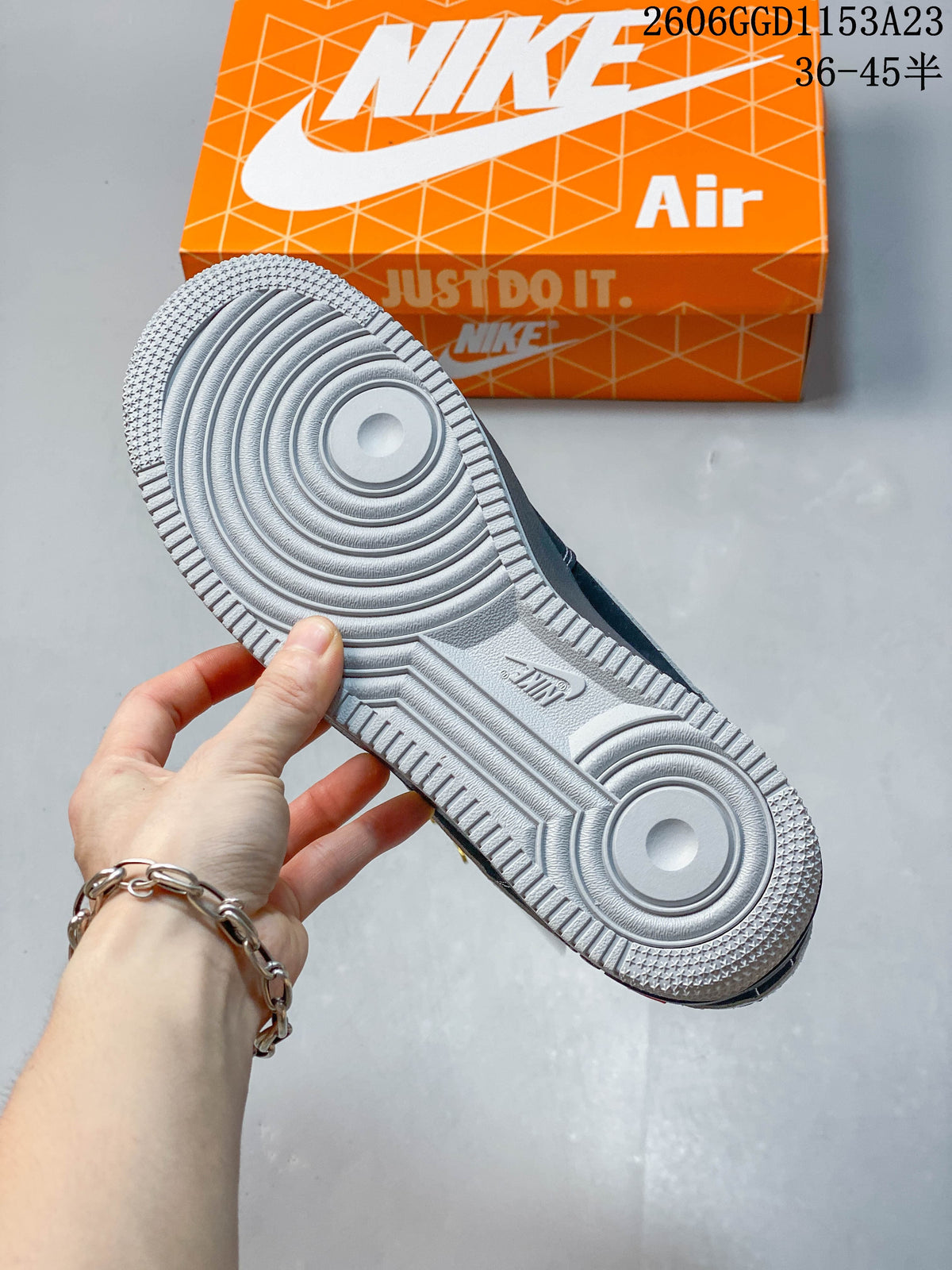 View of the sneaker outsole with circular tread and an orange Nike shoebox behind it