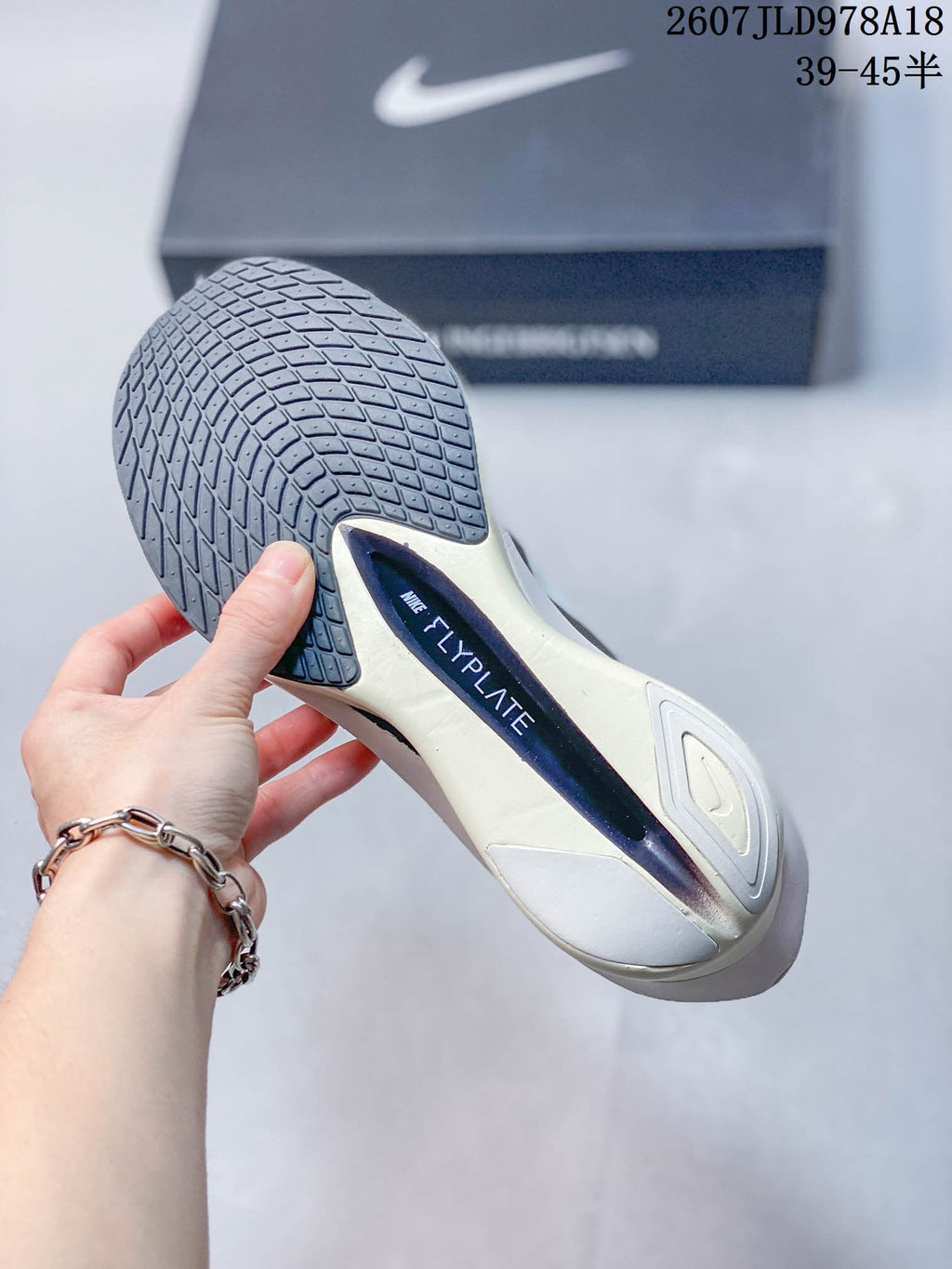 Close-up of the shoe outsole showing a dark patterned tread and visible Flyplate branding.