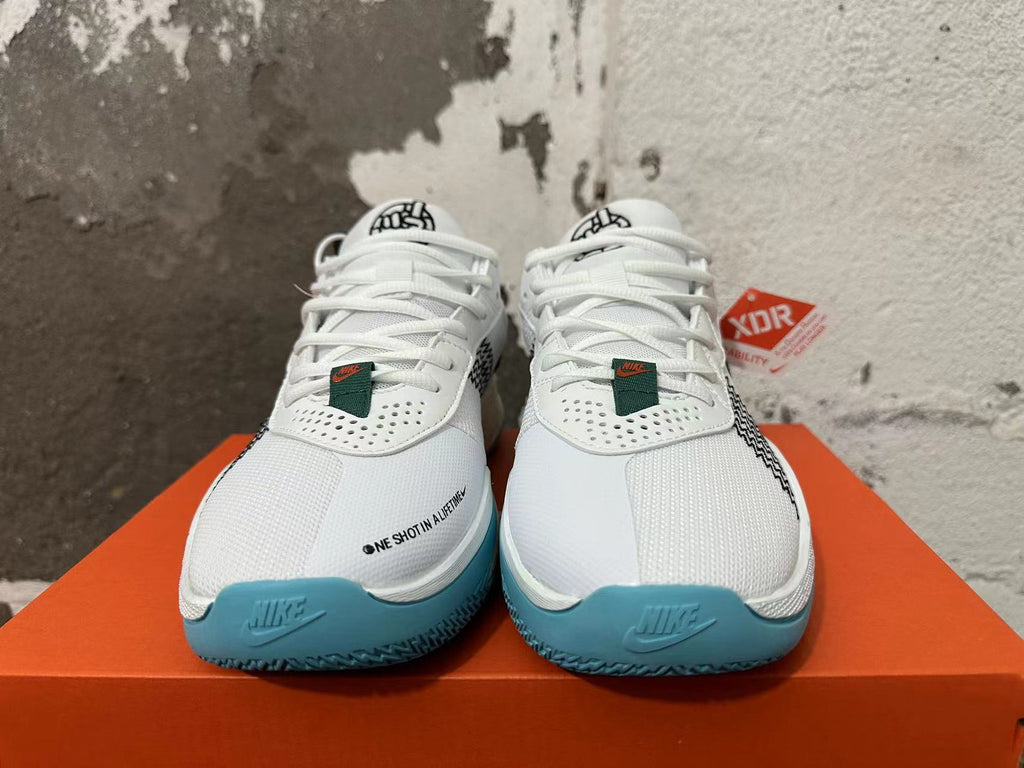 Front view of white Nike basketball shoes with perforated panels and blue outsole edges