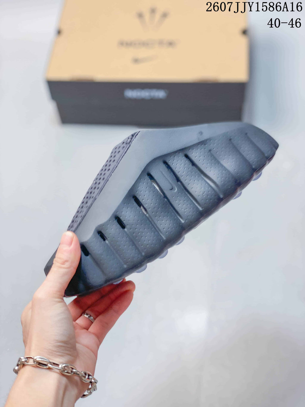 Side and outsole view showing the sculpted profile, deep grooves, and textured black-gray sole.